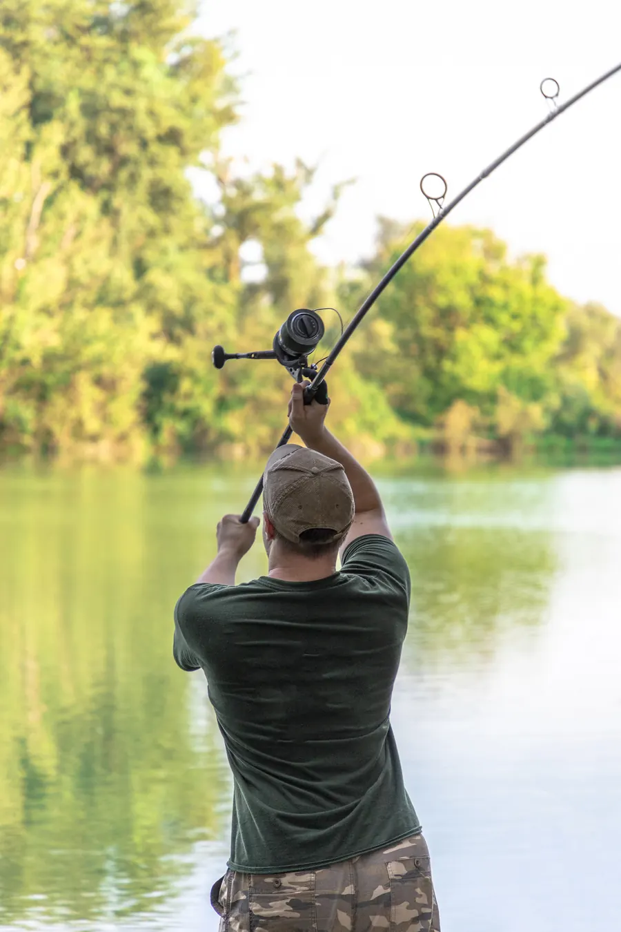An angler casting a carp rod across a lake