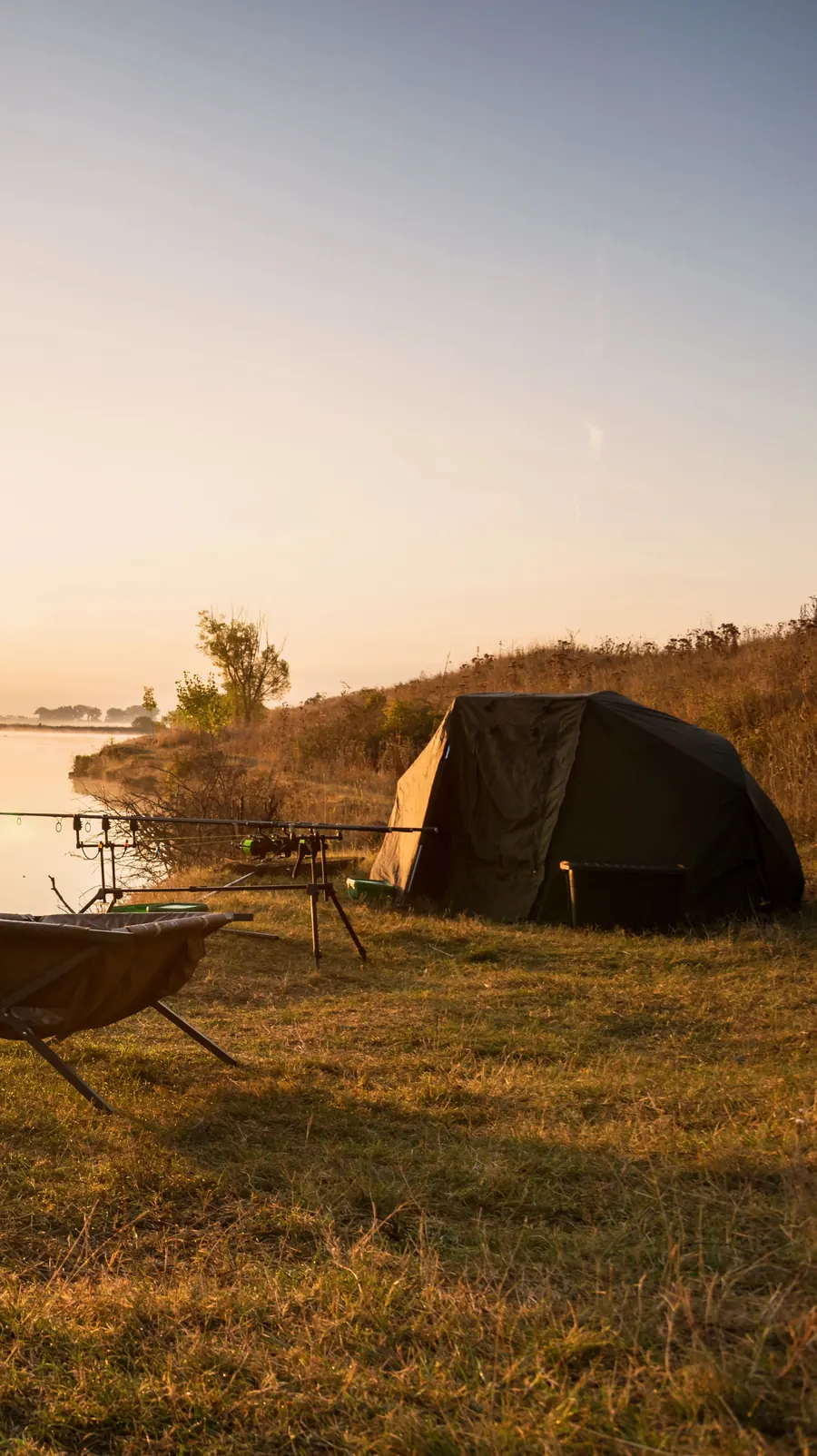 A bivvy and rods set up on the bank at sunrise