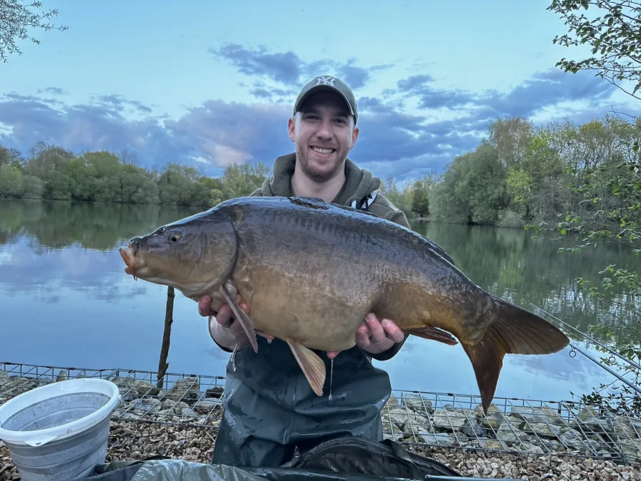 Glenn, who makes Ghillie, holding a mirror carp on the bank